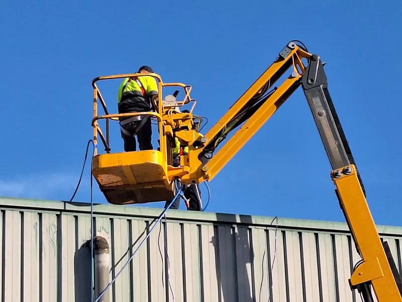 Operarios trabajando en altura con plataforma elevadora en una nave industrial